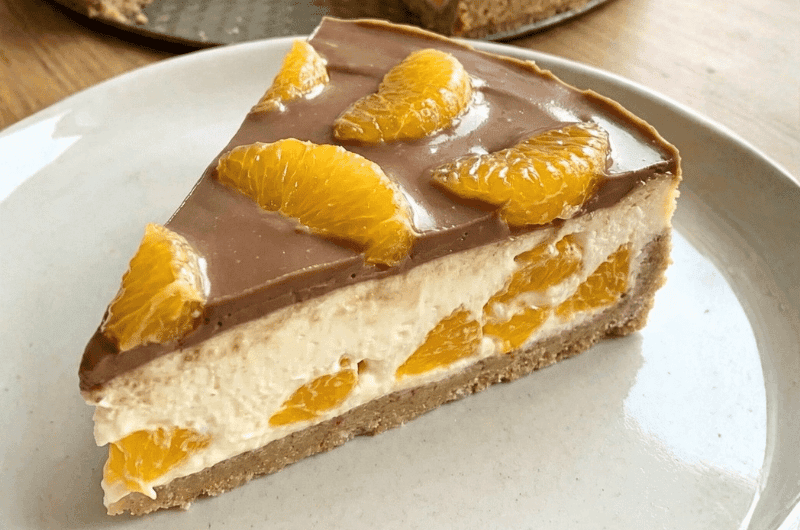 Kawałek fit sernika na zimno z pomarańczą i polewą z czekolady bez cukru.